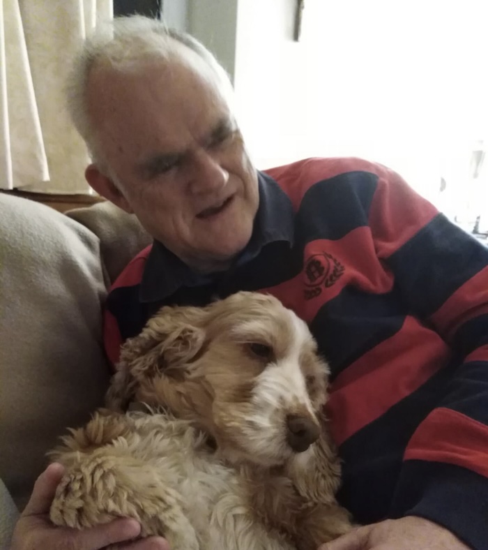 a man and his long eared dog snuggling into each other on the couch