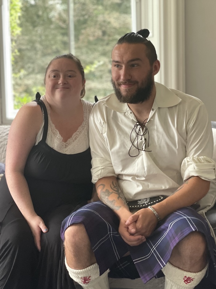 two happy people on a couch with one of them wearing a kilt