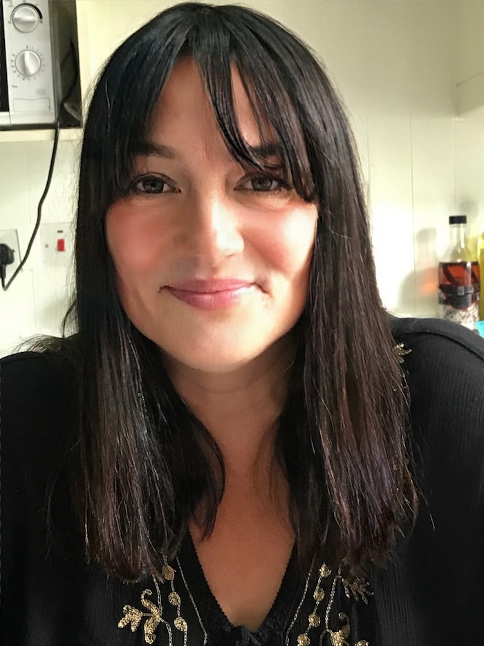 person with long straight black hair up close to the camera and smiling