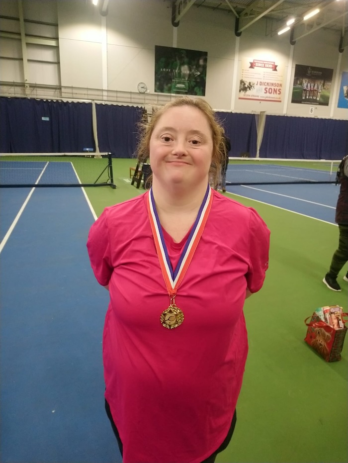 happy proud woman wearing red sports top and a medal around her neck